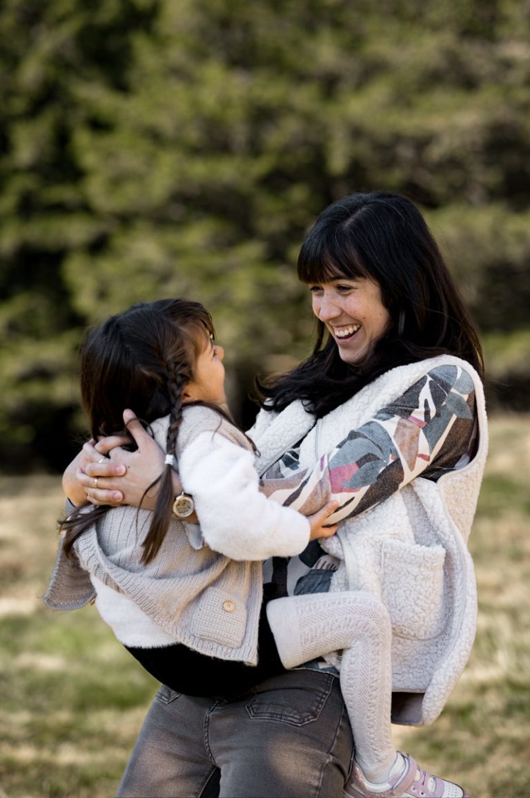 Photographie d'une maman portant sa fille, elles se sourient.